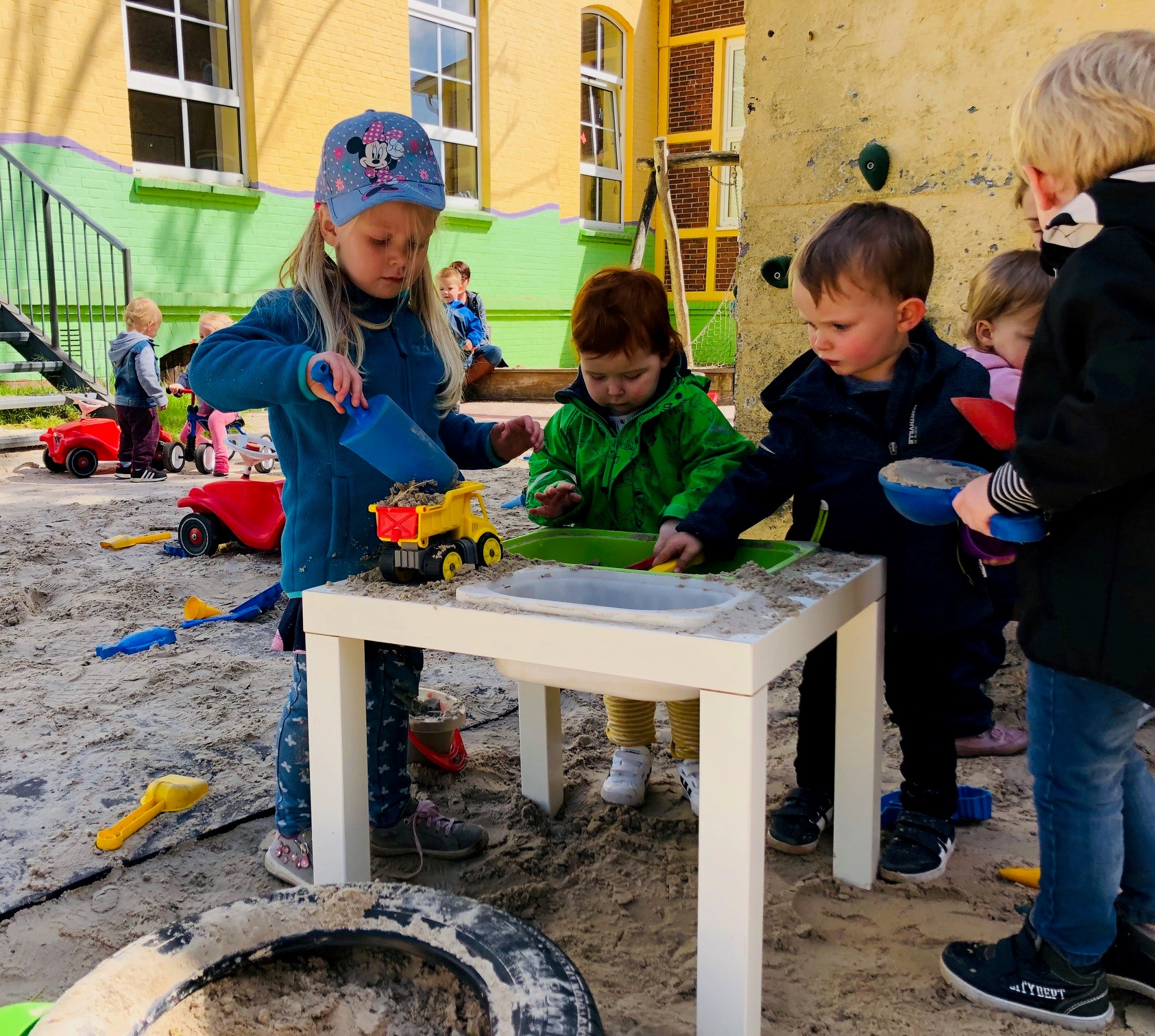Kinder spielen draußen mit Sand und mit Spielzeugen