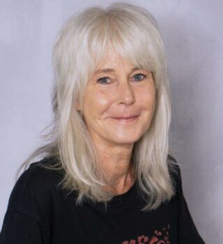 Nicola Kraus. Eine lächelnde Frau mit langen grauen Haaren