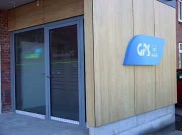 Der Eingang zu einem Gebäude der GPS Werkstatt Wilhelmshaven. Man sieht auch ein blaues "GPS Logo" Schild an einer Wand.