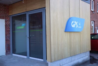 Der Eingang zu einem Gebäude der GPS Werkstatt Wilhelmshaven. Man sieht auch ein blaues "GPS Logo" Schild an einer Wand.