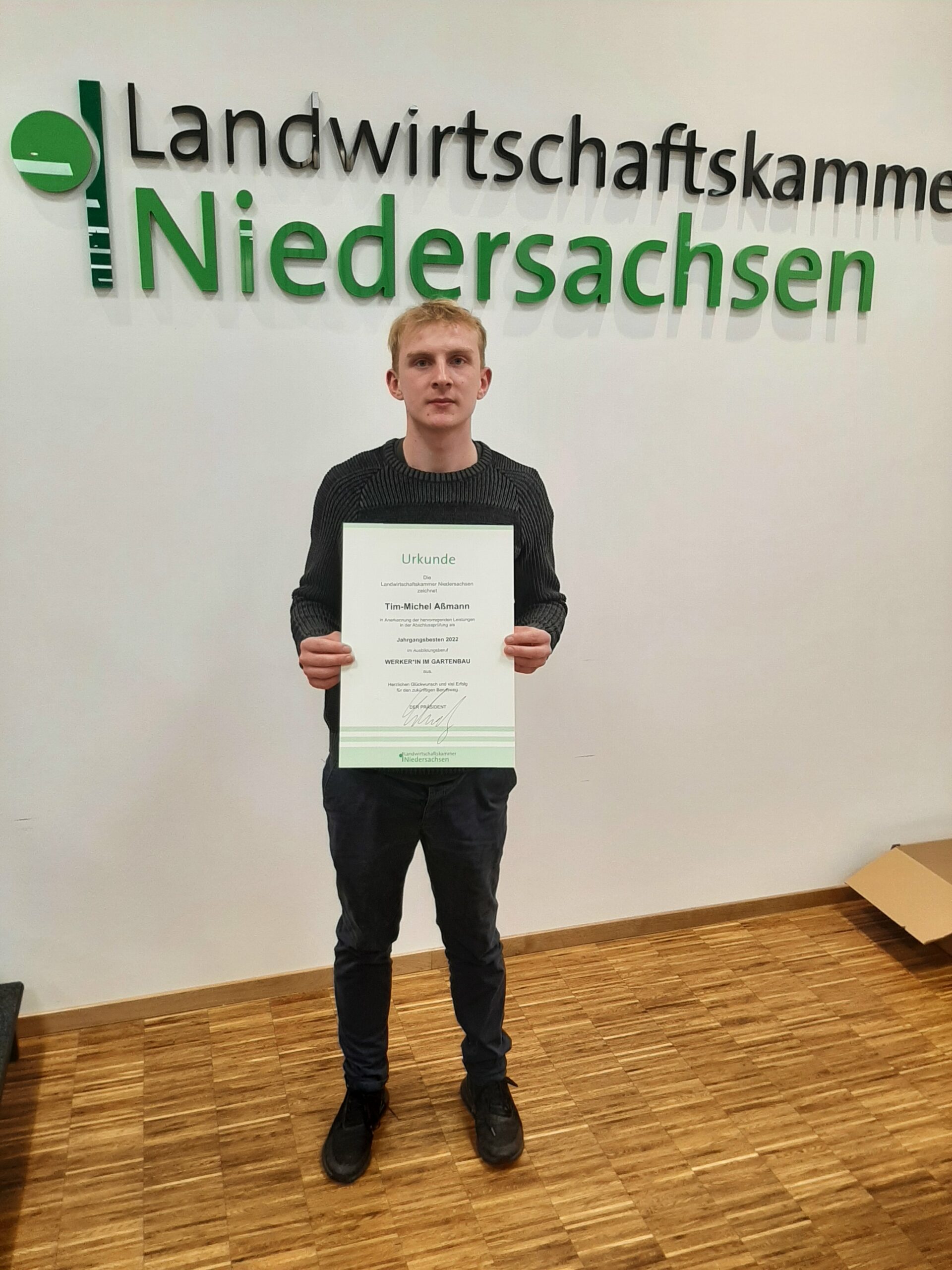 Ein Werker-Auszubildender bekommt eine Urkunde von der Landwirtschaftskammer Niedersachsen als Bester Werker Garten- und Landschaftsbau.