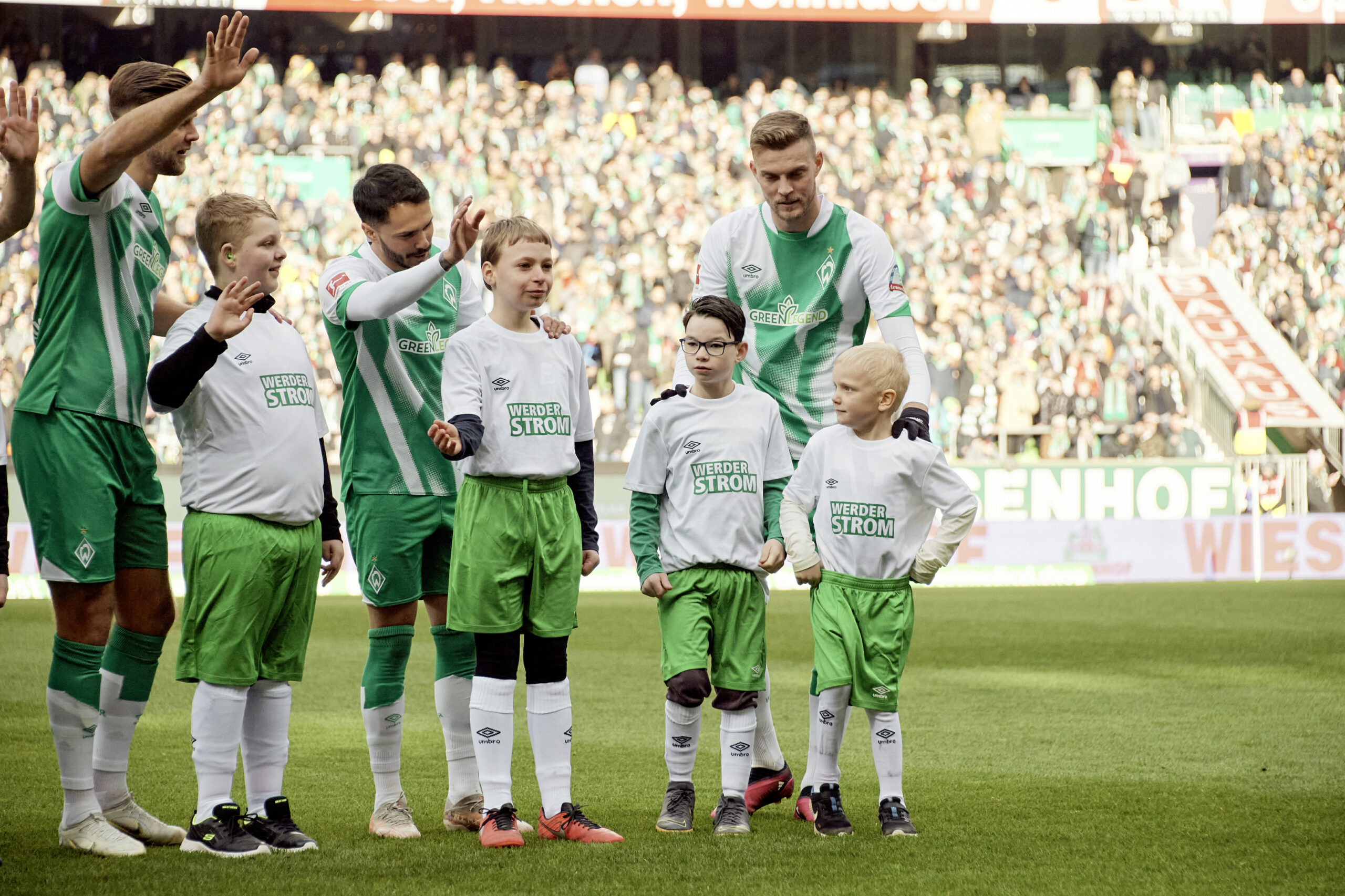 Fußballspieler vom Bundesliga Fußballverein Werder Bremen und kleine Kinder zusammen mit dem Publikum im Stadion