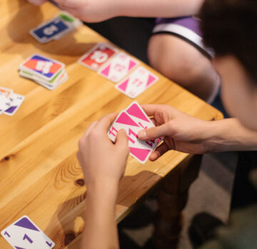 Kinder am Tisch. Sie spielen ein Kartenspiel.