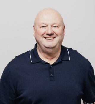 Ein Mann namens Frank Isenecker der keine Haare trägt.. Er hat einen schwarzen Pullover an.