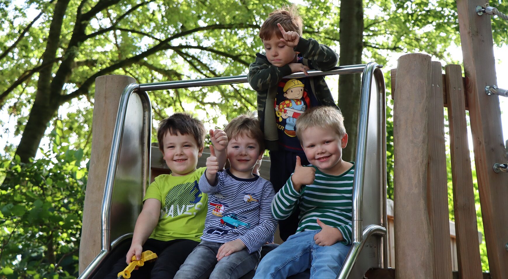 3 Kinder halten den Daumen hoch, ein Kind zeigt den Zeigefinger