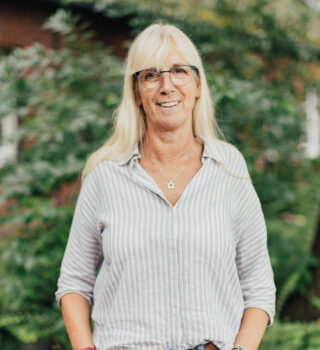 Eine Frau namens Claudia Loepp mit Brille und mit grauen Pullover. Sie hat langes blondes Haar.