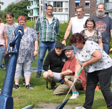 Man sieht Mitarbeiter der Tagesstätte Ebkeriege und Beschäftigte beim Minigolfplatz beim Havenhaus Minigolf draußen spielen