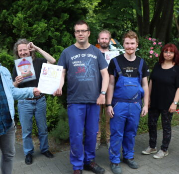 Gruppenfoto mit drei Teilnehmer von der Prüfgruppe Büro für Leichte Sprache, mit Leiterin der Büro für Leichten Sprache Karin Mohr-Schindler, die Leiterin von der GPS Werkstatt Jeringhave Claudia Hashmi und zwei GPS Werkstattbeschäftigte. Die Abteilung Büro für Leichte Sprache präsentiert die neue Ausgabe "LeiSa".