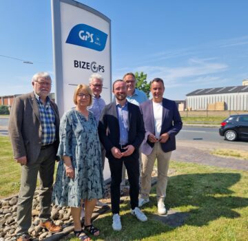 Man sieht auf dem Bild GPS Mitarbeiter und der Geschäftsführer der GPS zusammen mit einem Politiker auf dem Foto vor dem Bizeps Gebäude draußen bei schönen sonnigen Wetter.