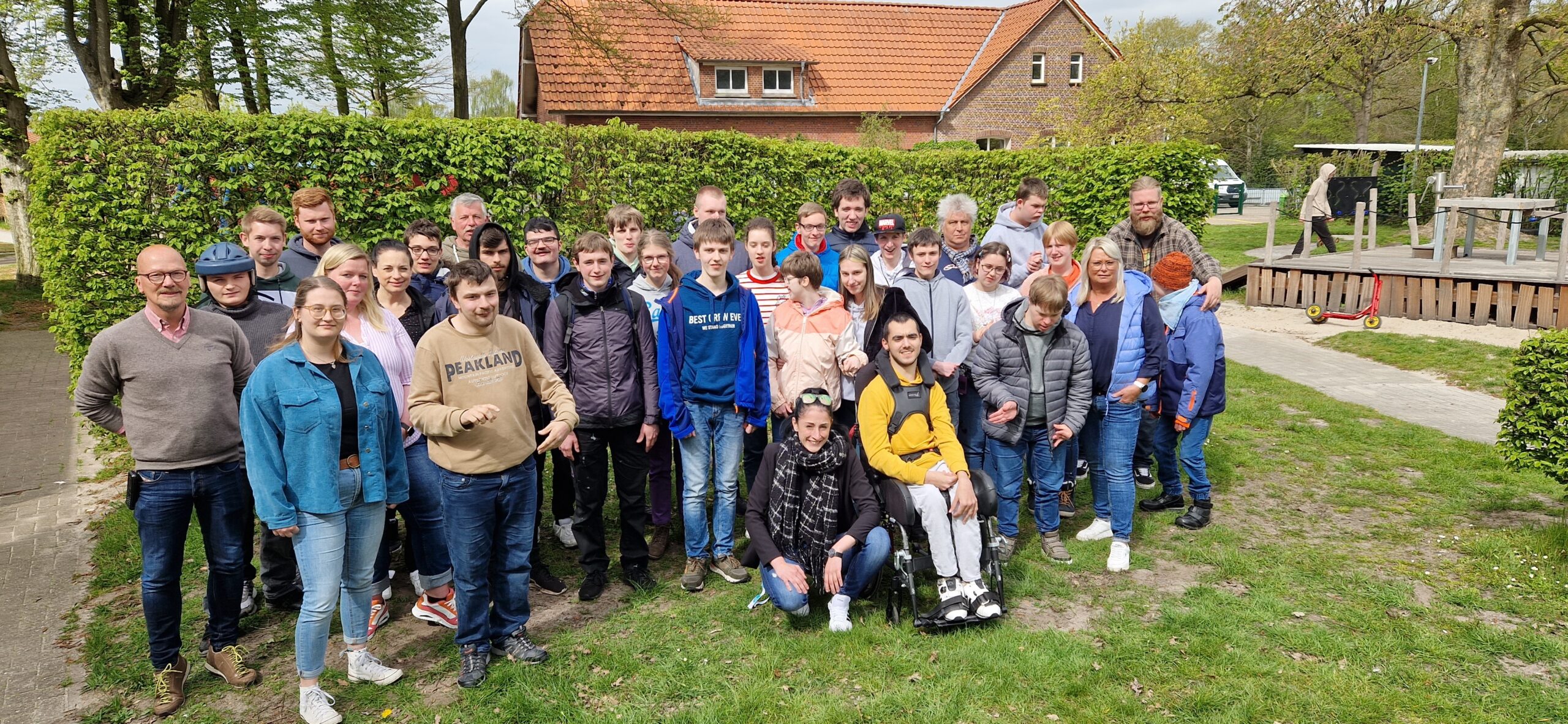 Eine Gruppe junger Menschen und der Einrichtungsleiter Friedrich Fittje draußen im Garten. Ein Gruppenfoto von der Dorfschule Mansie.