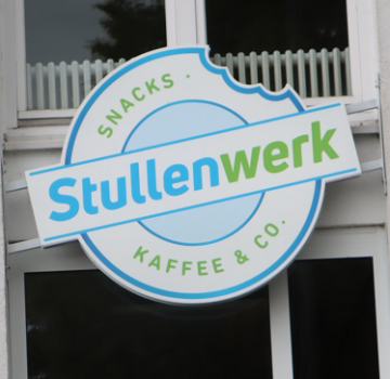 Weißes Gebäude mit Firmenlogo "Stullenwerk".