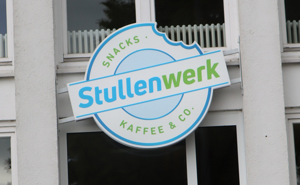 Weißes Gebäude mit Firmenlogo "Stullenwerk".