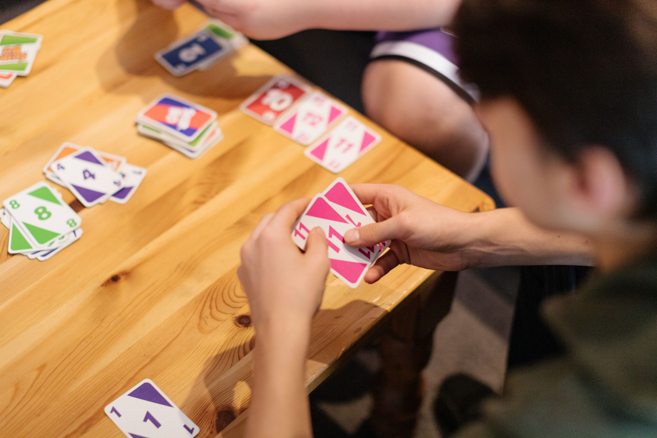 Kinder am Tisch. Sie spielen ein Kartenspiel.