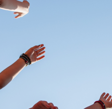 4 Menschen halten die Hände hoch in Richtung zum Himmel.